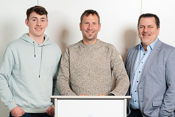 Gruppenfoto: Personen des Aufsichtsrats hinter einem Pult