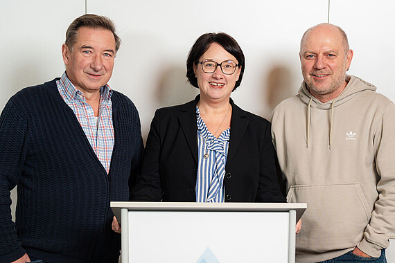 Gruppenfoto: Personen des Aufsichtsrats hinter einem Pult