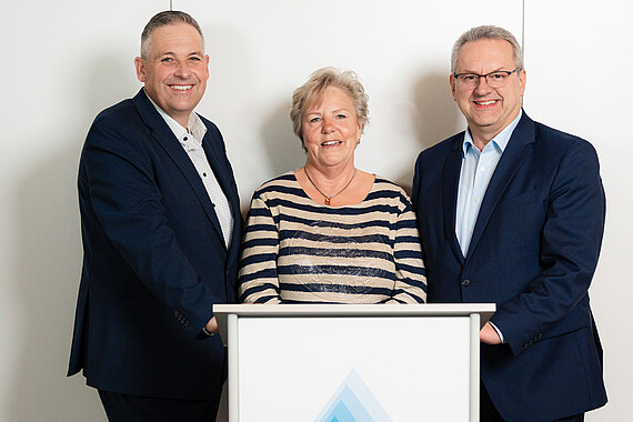 Gruppenfoto: Personen des Aufsichtsrats hinter einem Pult